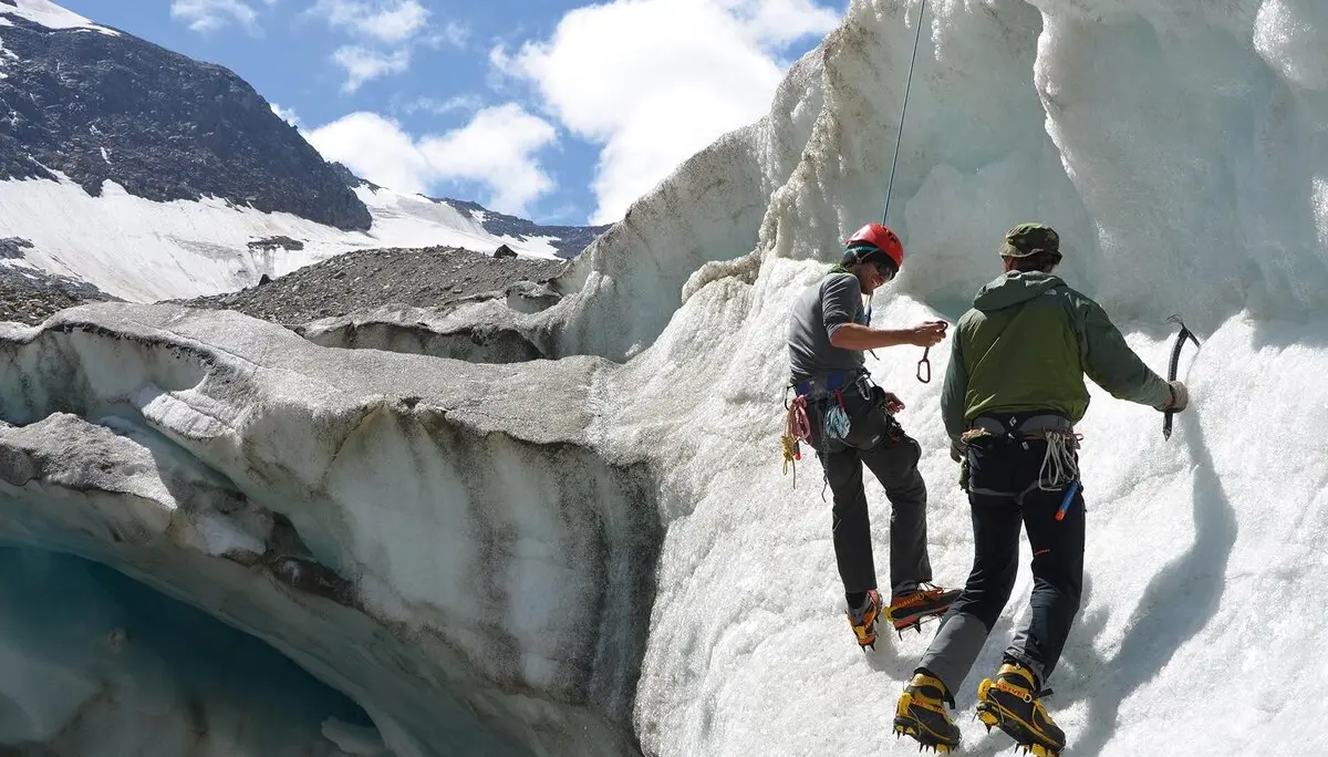 Es sind zwei Männer mit Eispickel und Steigeisen zu sehen, die sich an einer Eiswand aufhalten. Einer von beiden ist mit einem Seil gesichert. | © DAV Münster