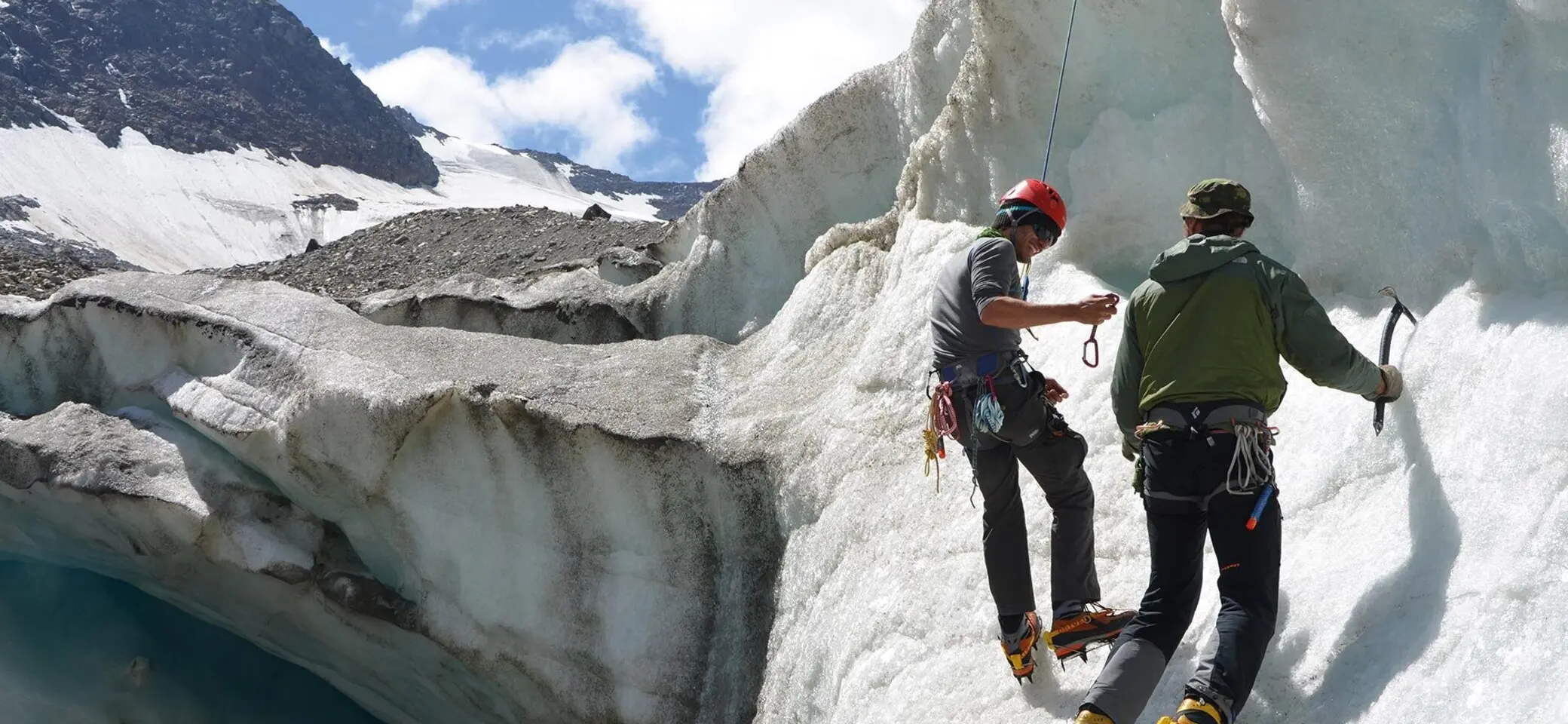 Es sind zwei Männer mit Eispickel und Steigeisen zu sehen, die sich an einer Eiswand aufhalten. Einer von beiden ist mit einem Seil gesichert. | © DAV Münster