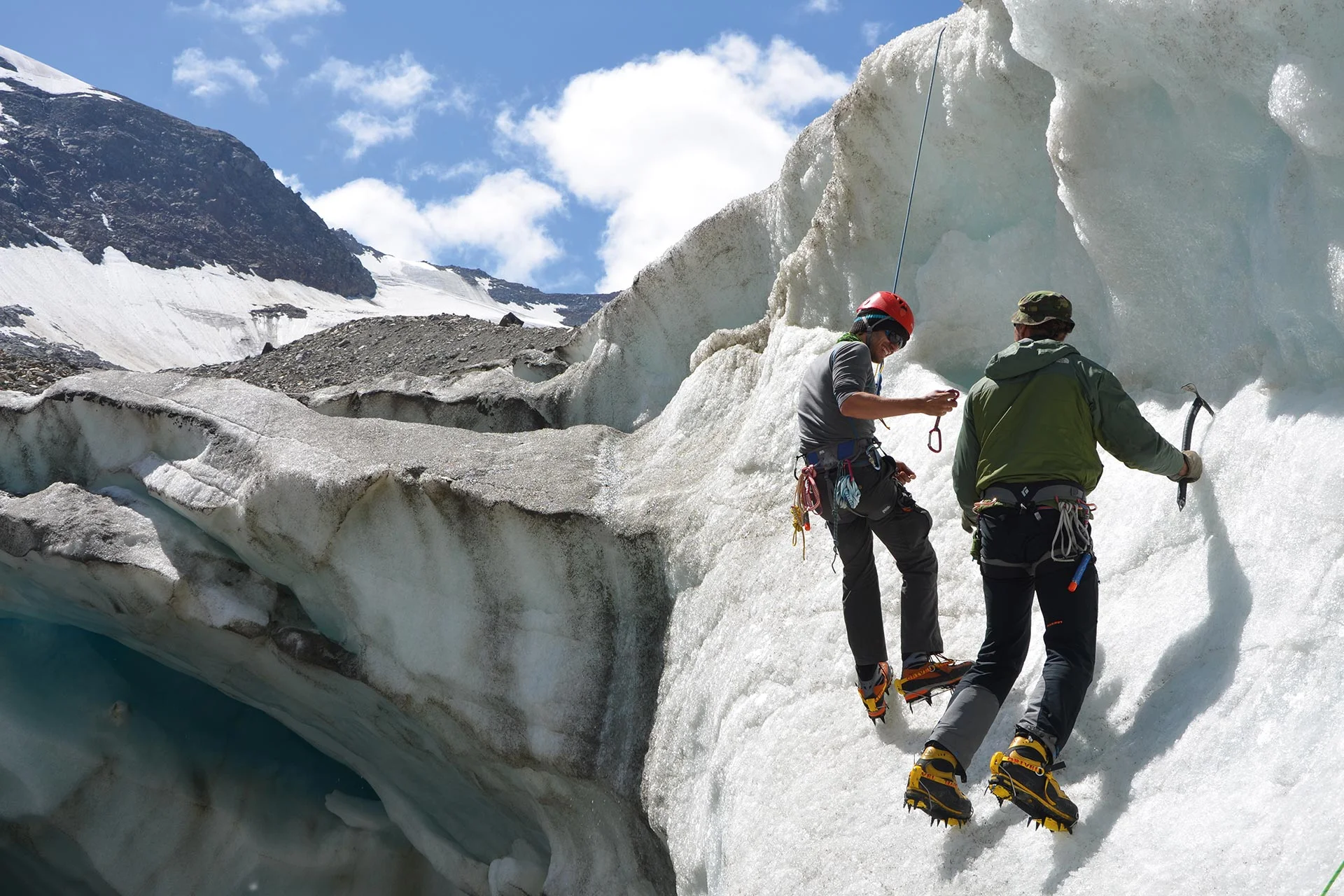 Es sind zwei Männer mit Eispickel und Steigeisen zu sehen, die sich an einer Eiswand aufhalten. Einer von beiden ist mit einem Seil gesichert. | © DAV Münster