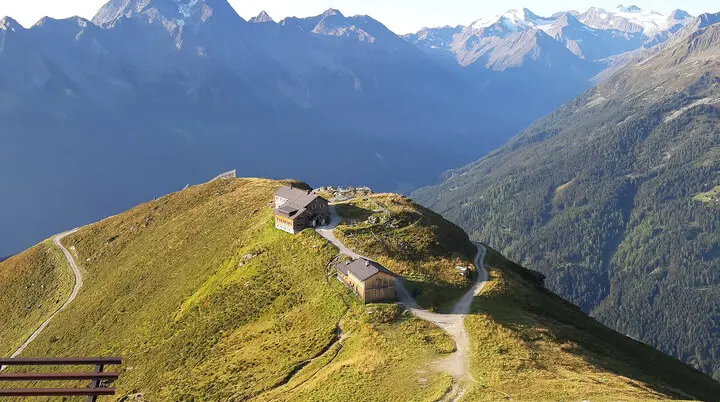 Hütten in den Bergen auf einer grünen Wiesen, im Hintergrund hohe Berge | © DAV Münster