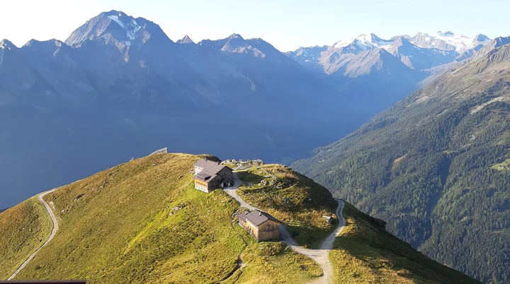 Hütten in den Bergen auf einer grünen Wiesen, im Hintergrund hohe Berge | © DAV Münster