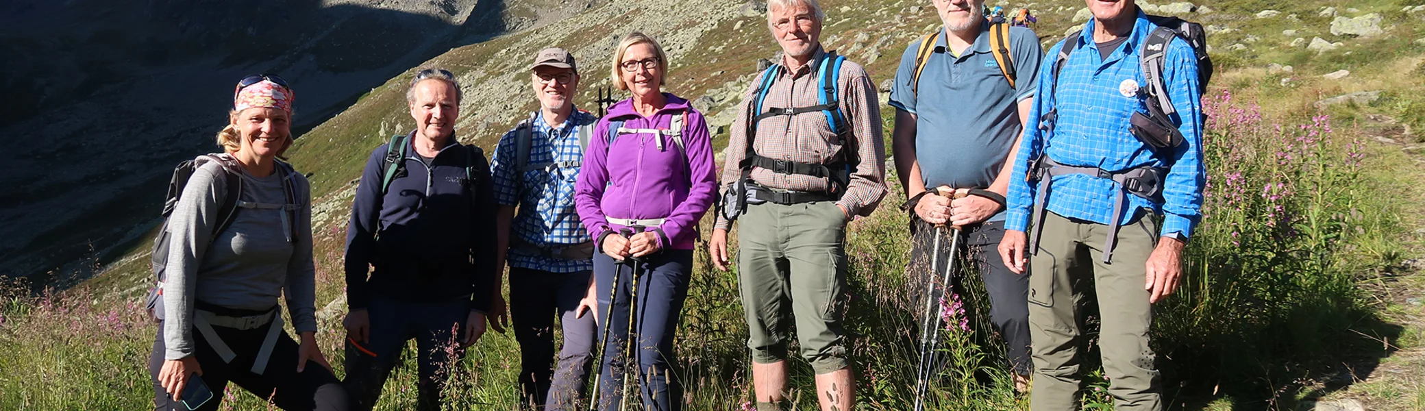 Es sind sieben Wanderer auf eine Wiese zu sehen, im Hintergrund sind Berge | © DAV Münster
