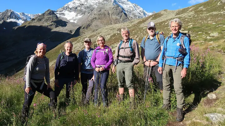 Es sind sieben Wanderer auf eine Wiese zu sehen, im Hintergrund sind Berge | © DAV Münster