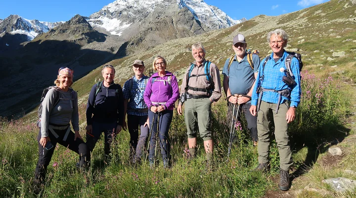 Es sind sieben Wanderer auf eine Wiese zu sehen, im Hintergrund sind Berge | © DAV Münster